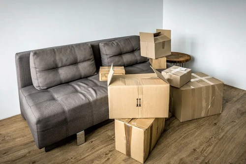 A collection of cardboard boxes sitting next to a sofa in a living room, ready for a move.